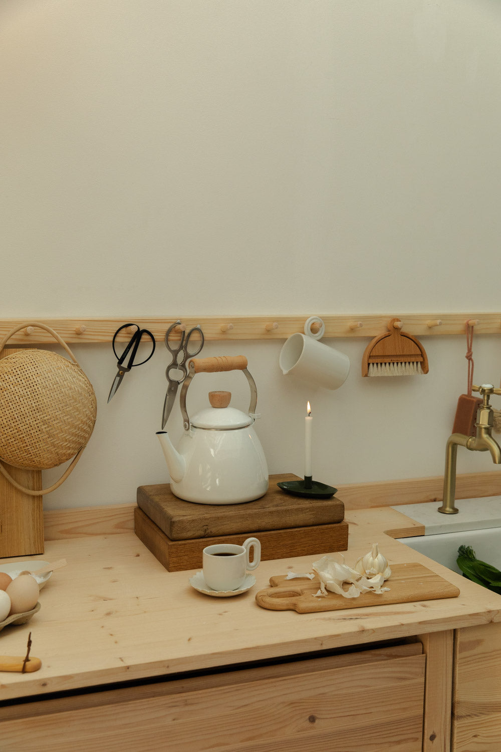 Kitchen counter with a white teapot, cup, and saucer on a wooden surface.