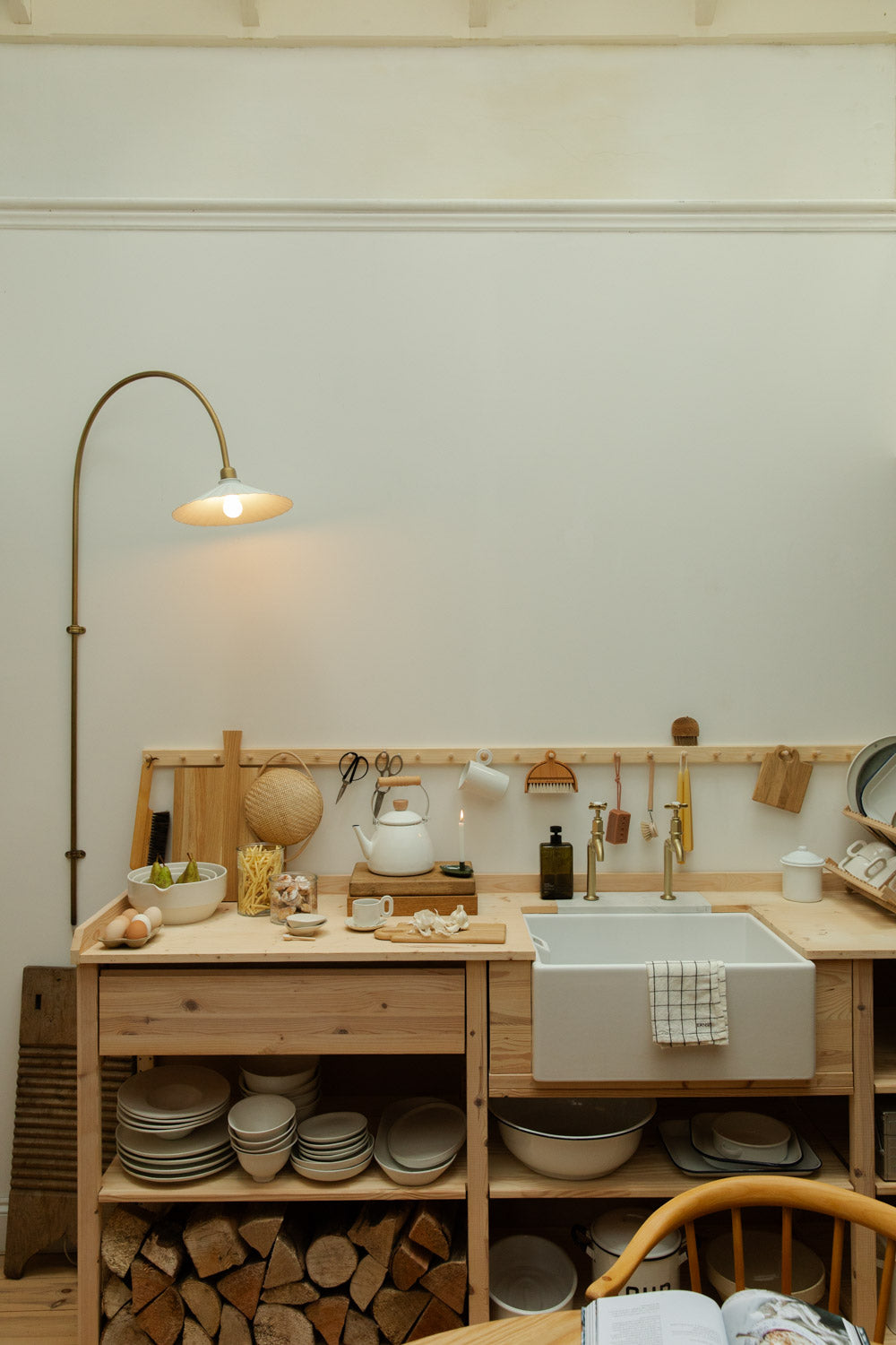 Wooden kitchen setup with a sink, shelves, and various kitchen items.