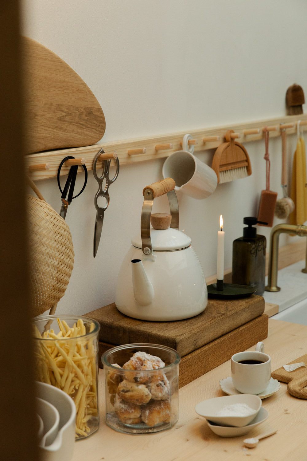 Kitchen counter with a white enamel kettle, glass jar of cookies, and various kitchen items.