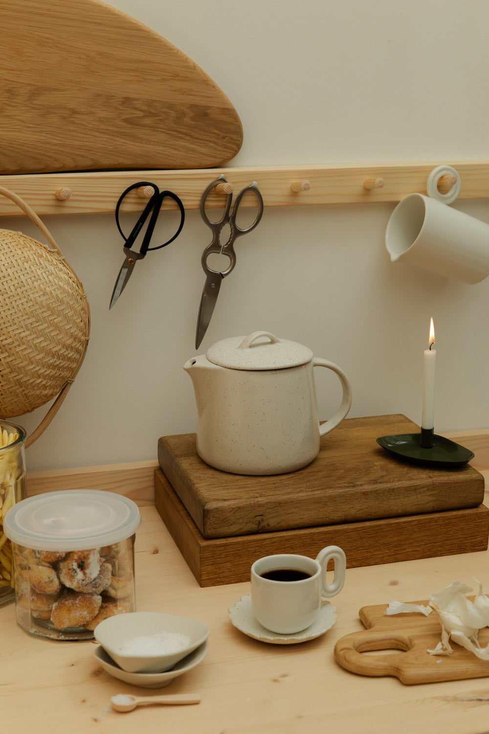 Tea set on a wooden surface with a teapot, cups, and a candle.