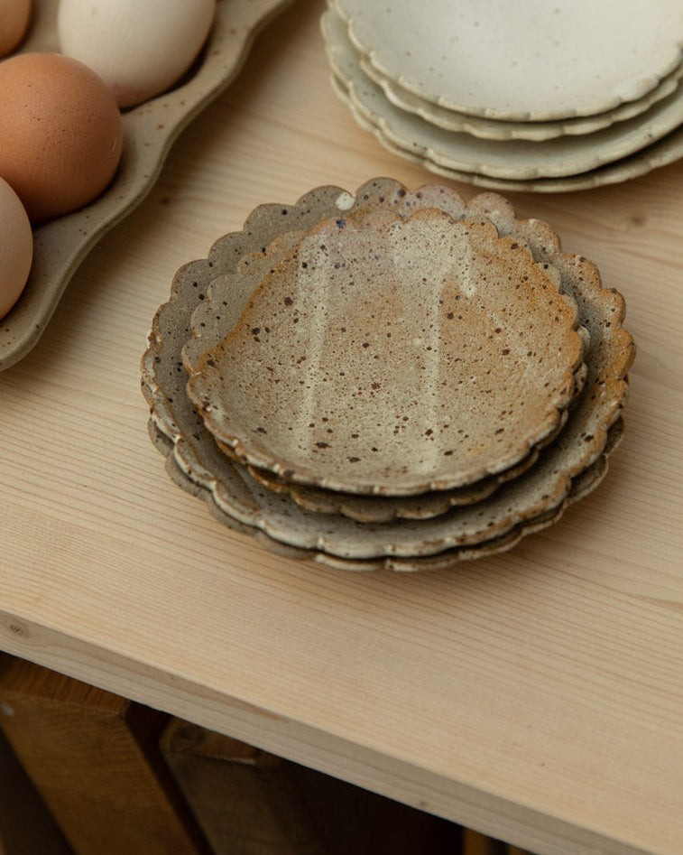Stacked ceramic plates on a wooden surface with eggs in the background