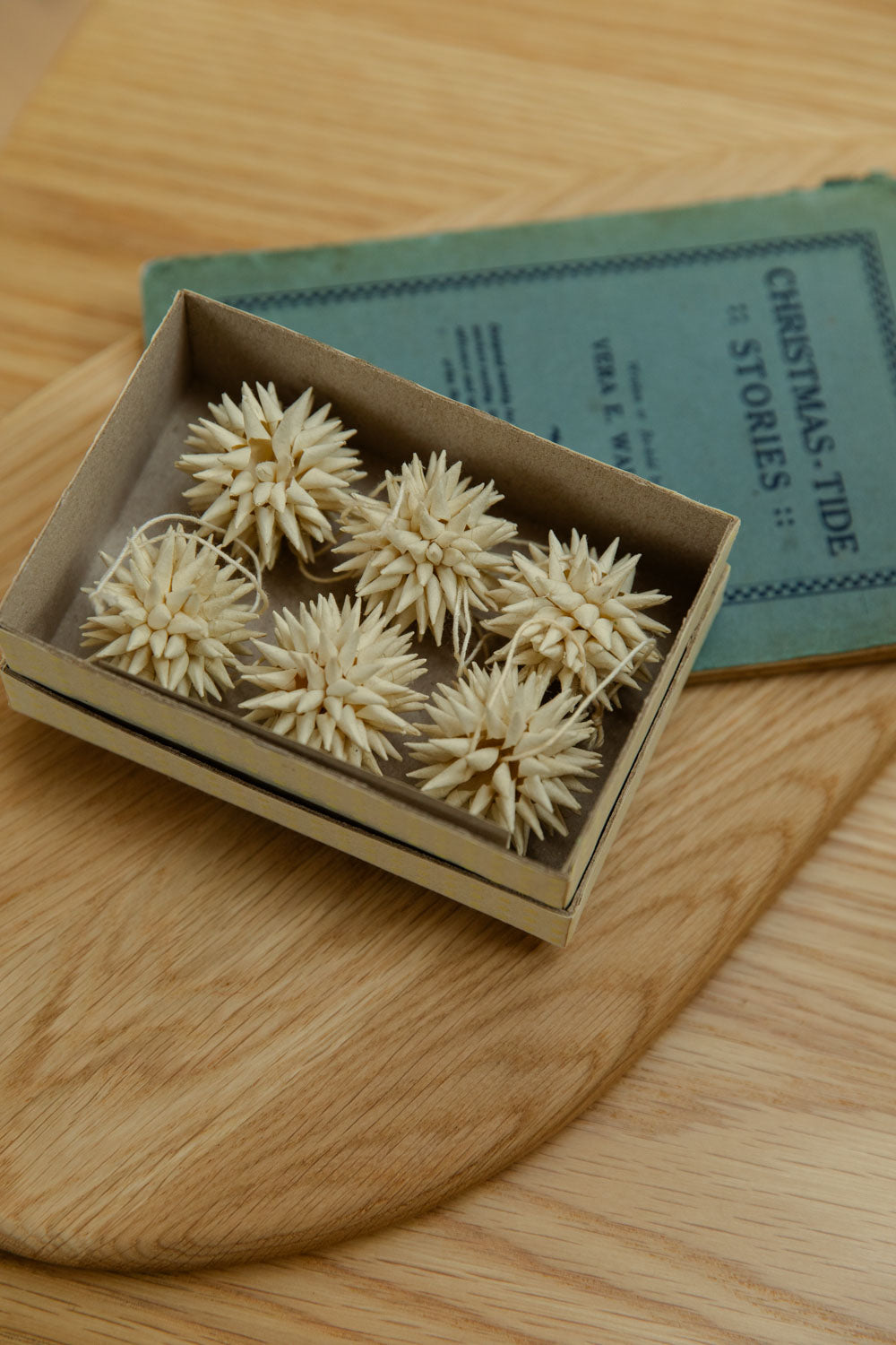 Small decorative items in a box on a wooden surface with a book in the background