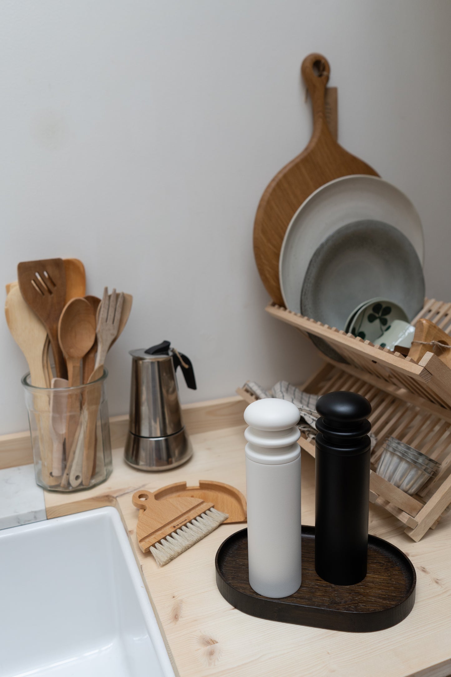 Kitchen counter with wooden utensils, a coffee press, and a dish rack.
