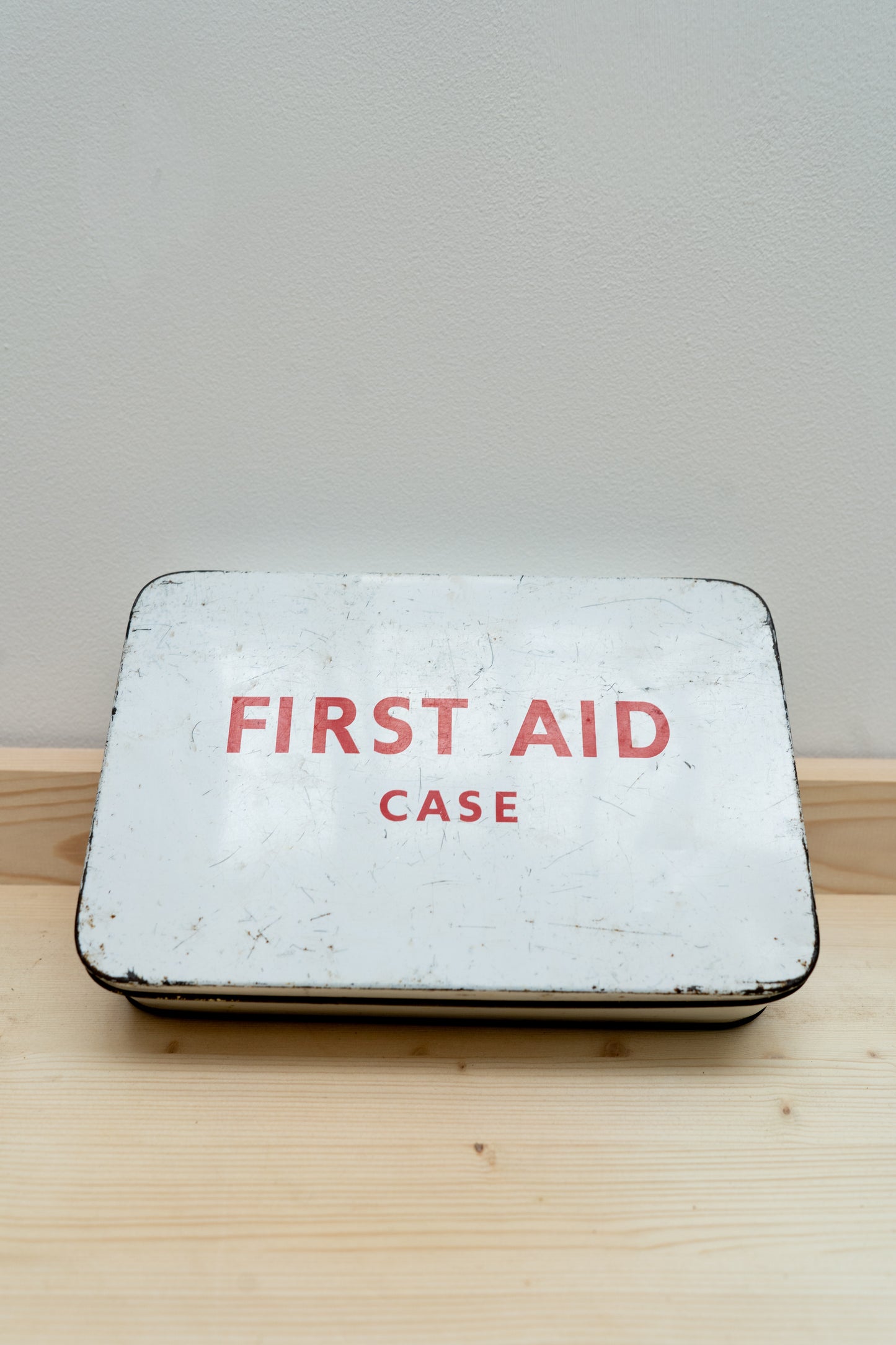 Vintage-style first aid case with 'FIRST AID CASE' text on a wooden surface.