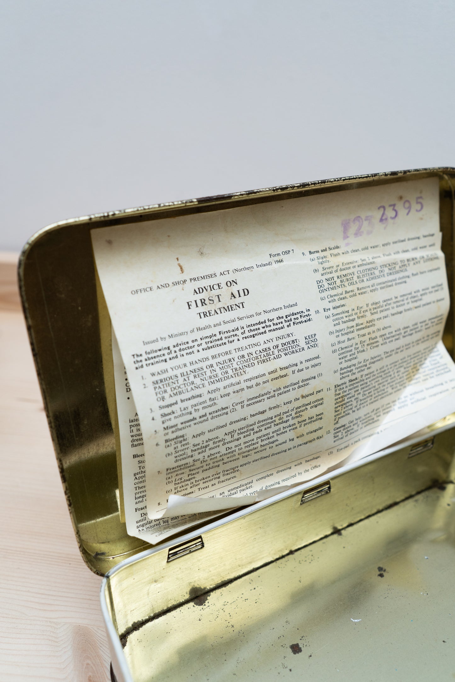 Vintage first aid kit with an open lid showing a printed label.