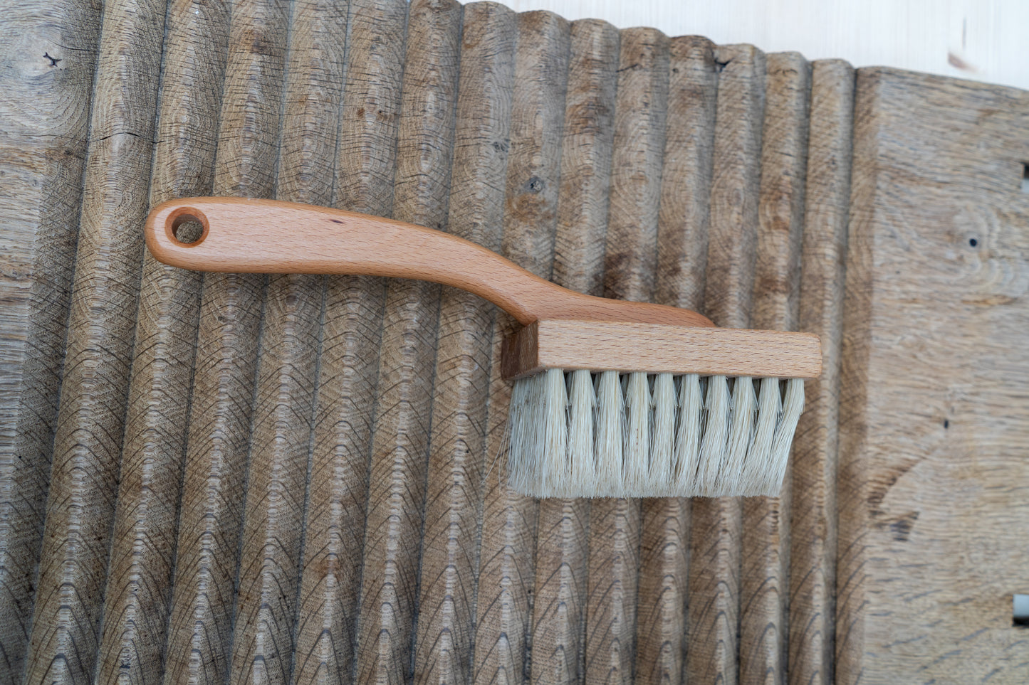 Wooden brush with a handle on a textured wooden surface