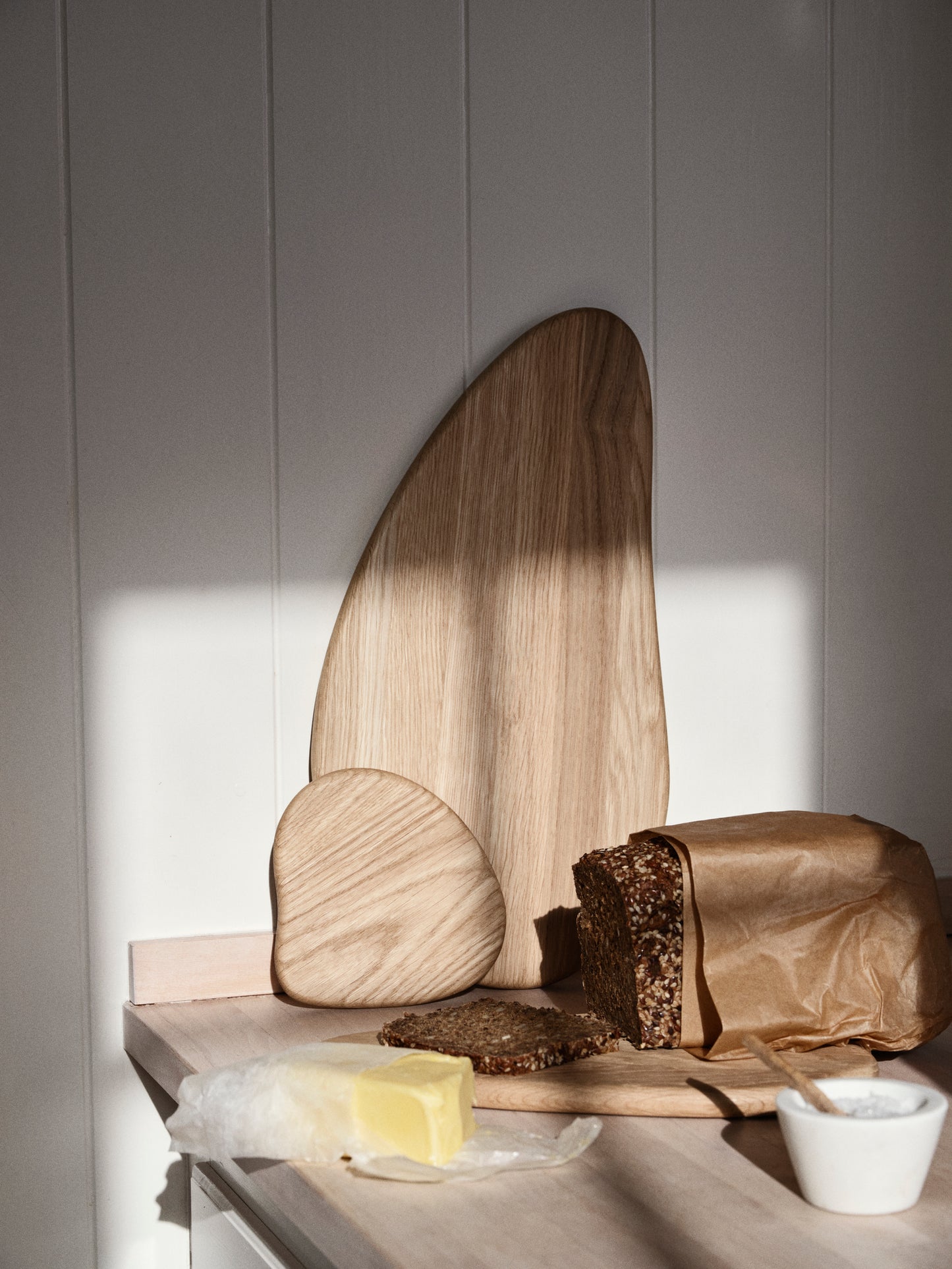 Wooden cutting board with bread and butter on a neutral background