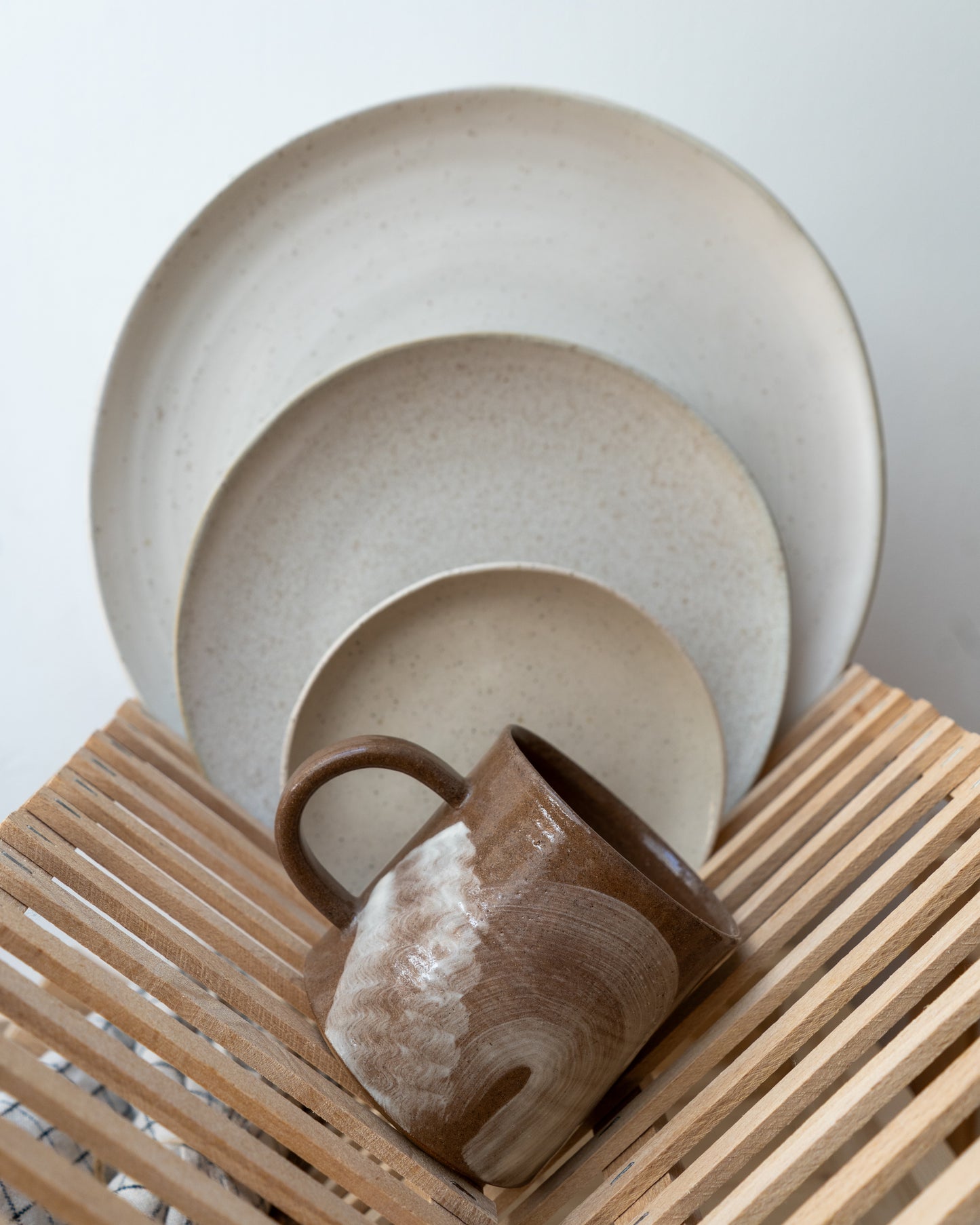 Ceramic plates and a mug on a wooden drainer with a light background