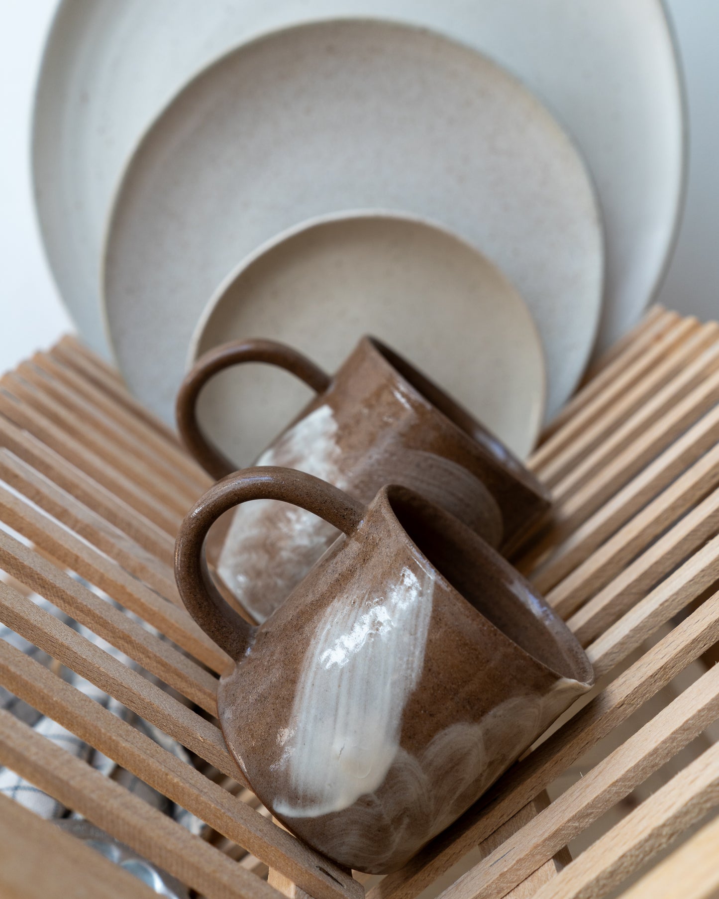 Ceramic mug and plates on a wooden dish drainer