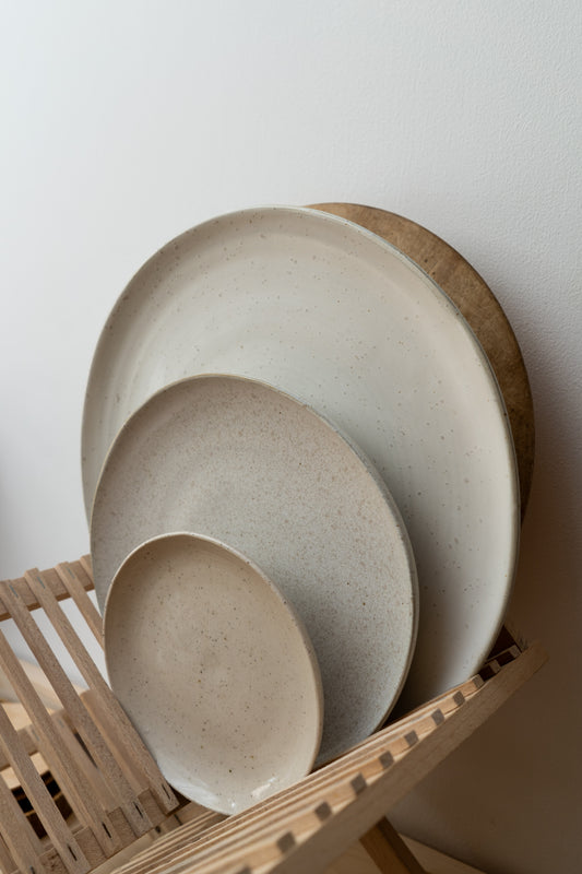 Set of ceramic plates on a wooden stand against a white wall