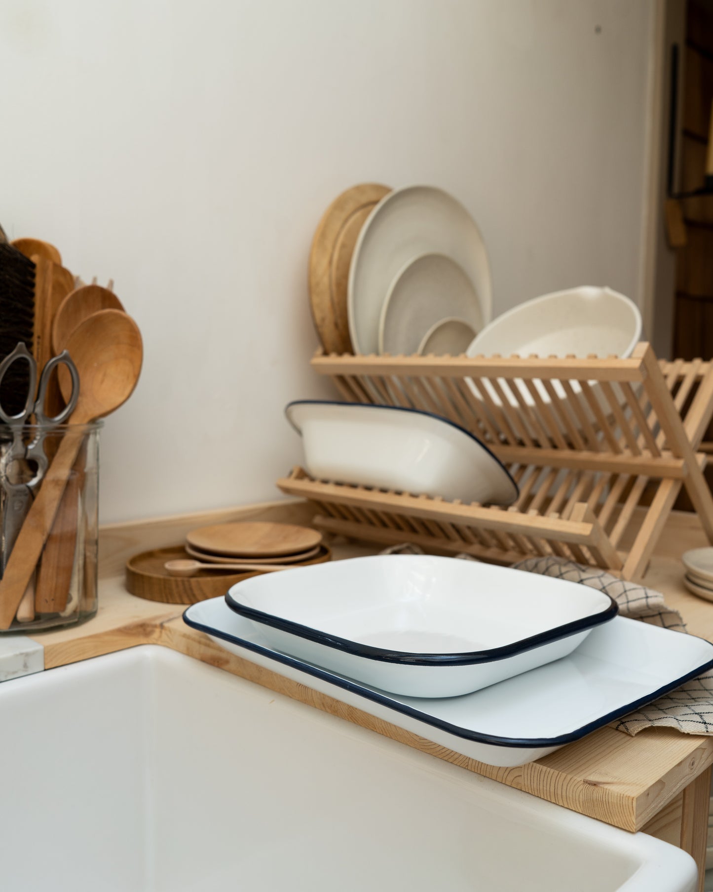 Dish drying rack with white and blue enamelware dishes on a kitchen counter.