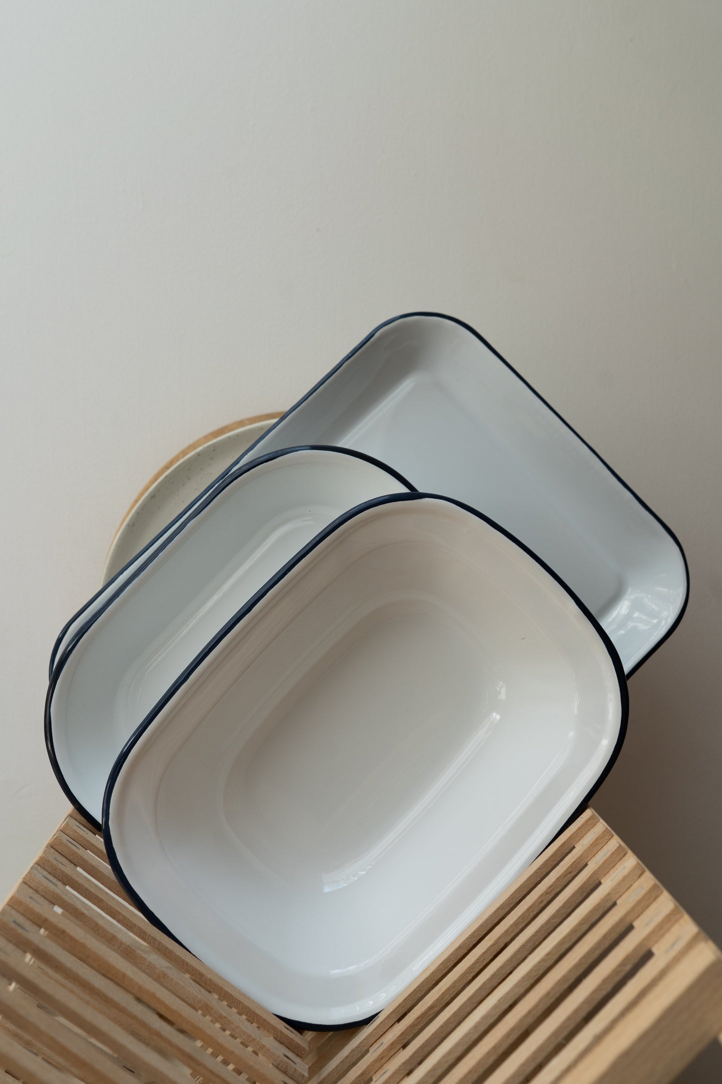 Two white enameled trays with dark navy rims on a wooden surface.