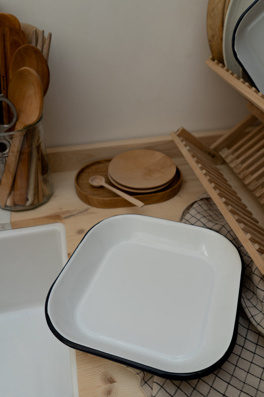 White enamel tray with navy rim on a wooden surface with kitchen utensils in the background.