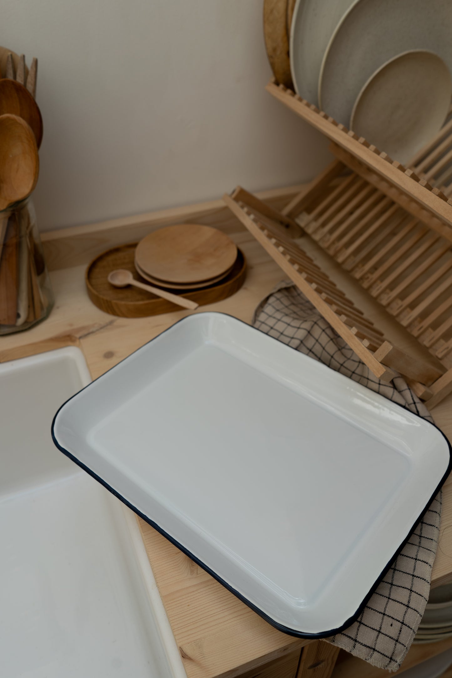 White enamel tray on a kitchen counter with wooden utensils and plates in the background.