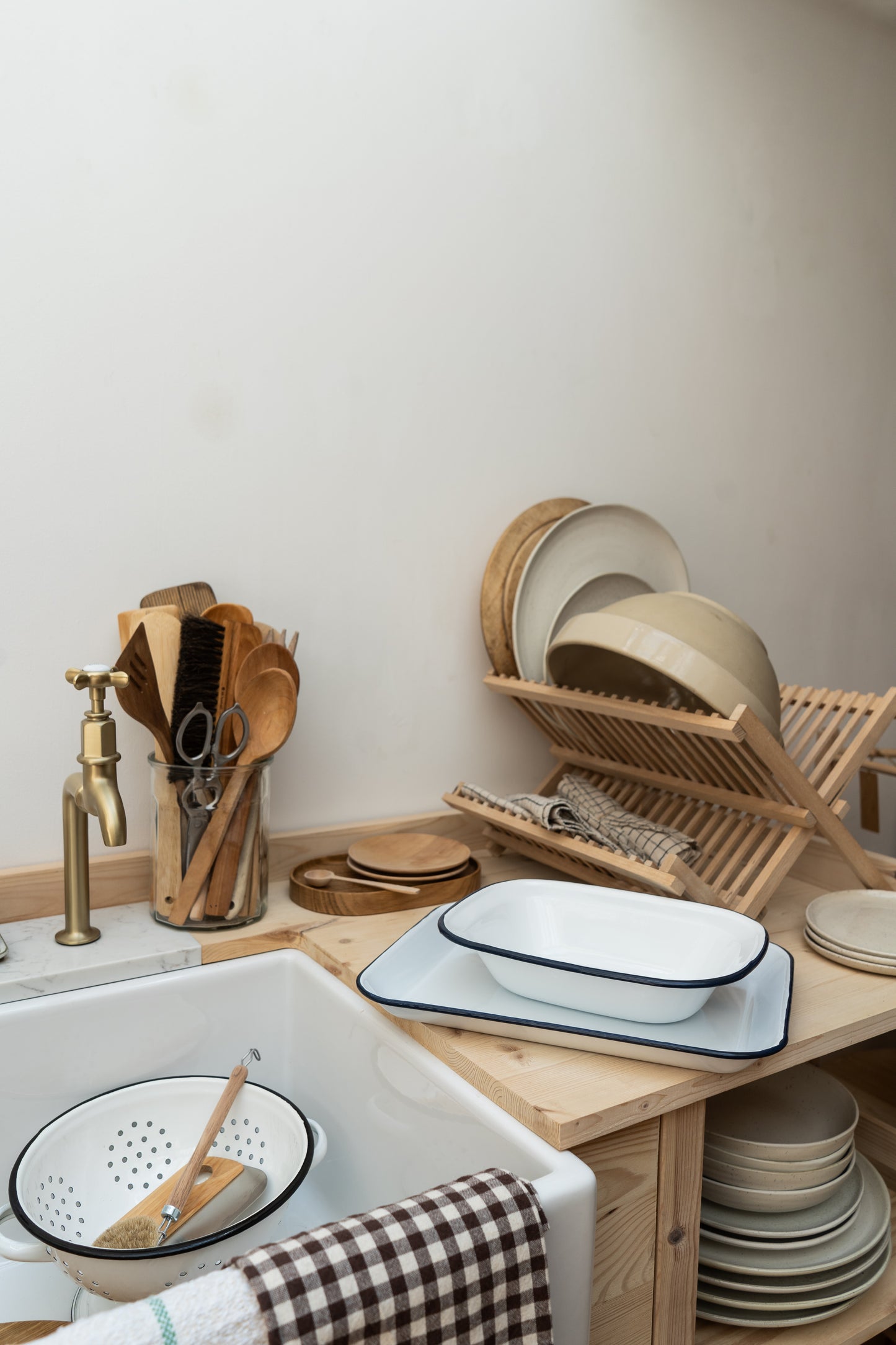 Kitchen setup with wooden utensils, plates, and bowls on a wooden shelf.