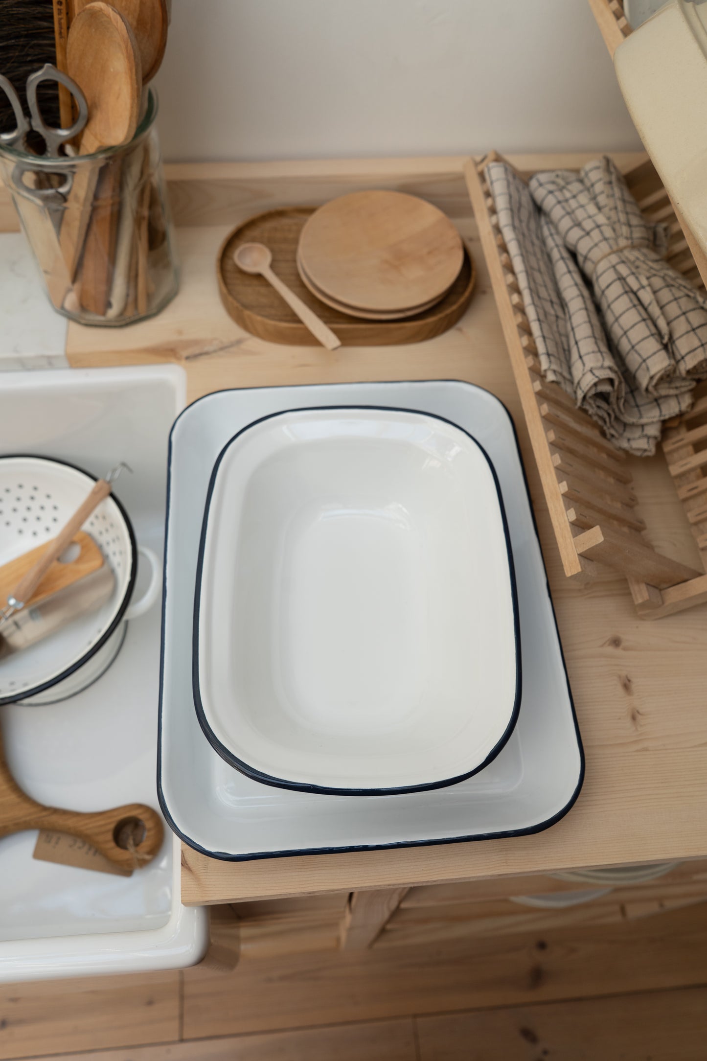 White enamel tray with navy rim on a wooden surface with kitchen utensils and items.