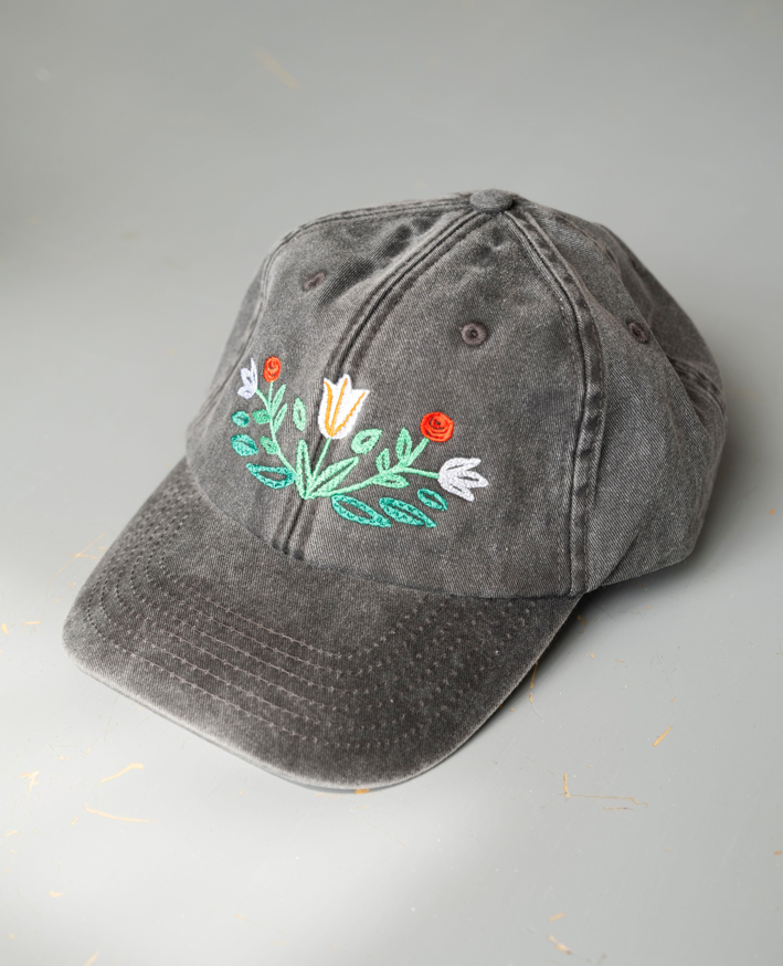 Gray black cap with floral embroidery on a light gray background