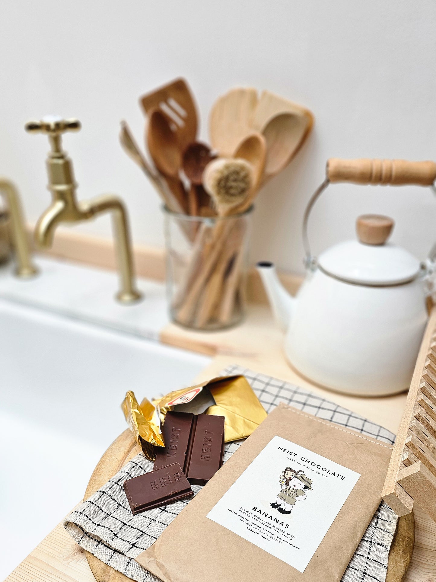 Chocolate package, chocolate bars, and a teapot on a kitchen counter.