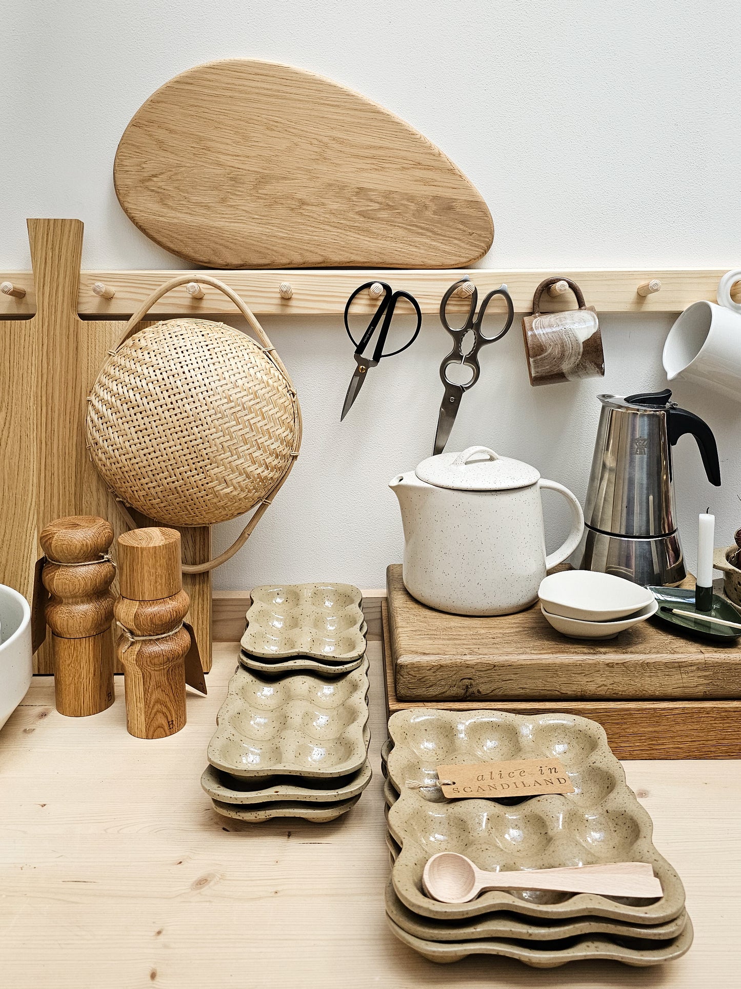 Kitchen items including a cutting board, scissors, a coffee maker, and ceramic trays on a wooden shelf.