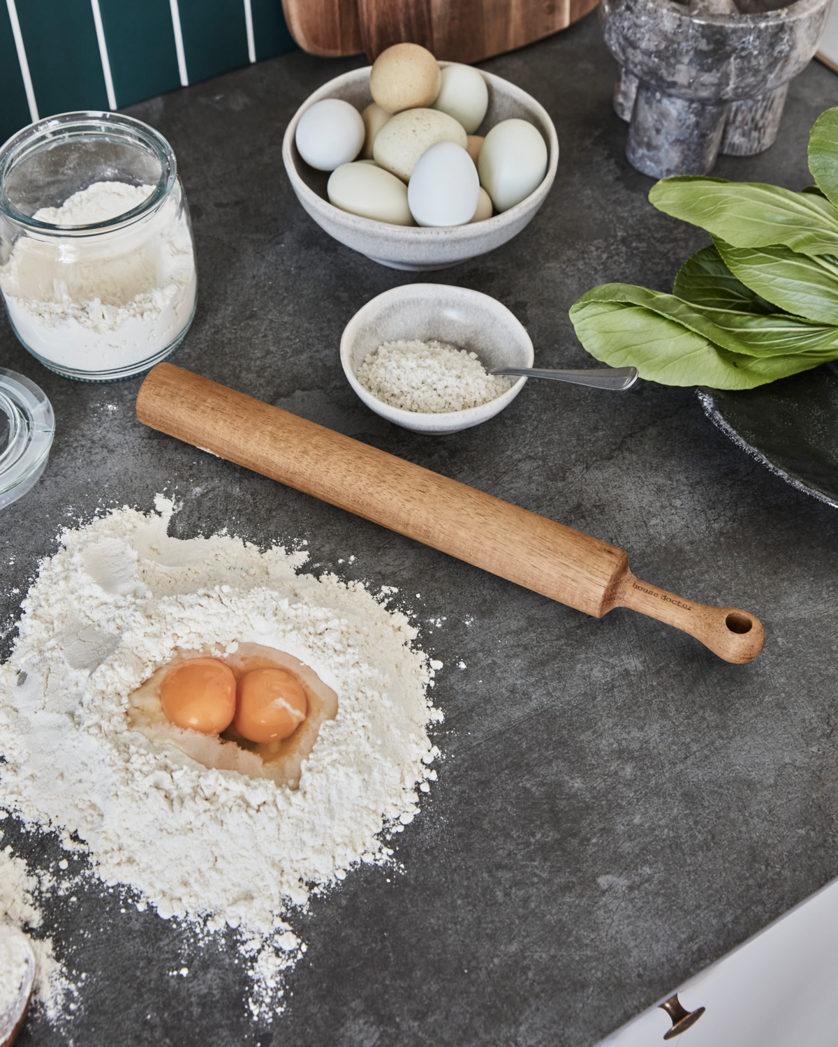 Ingredients for baking on a dark surface with a rolling pin and flour.