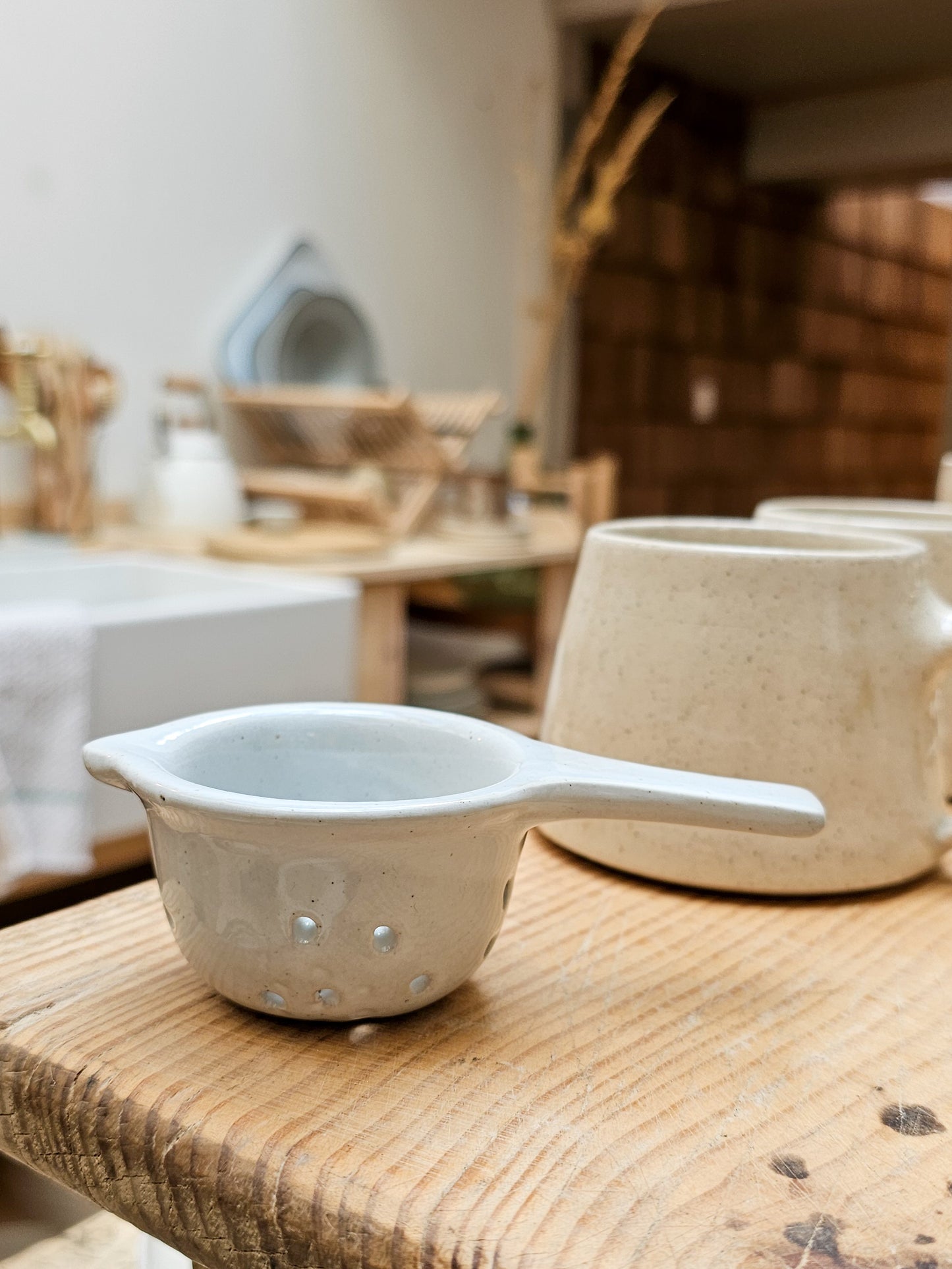 Ceramic tea strainer on wooden board.