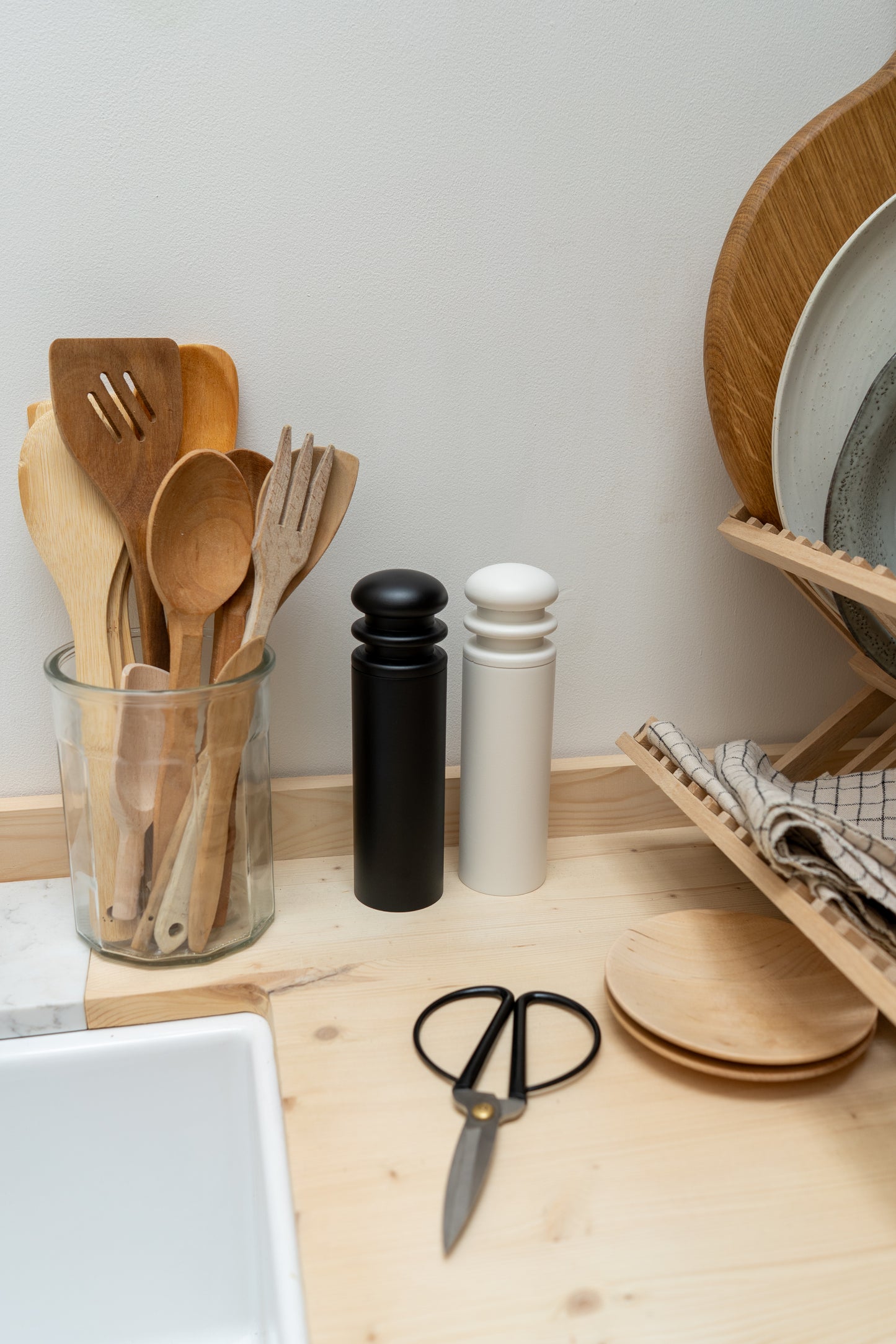 Kitchen counter with wooden utensils, salt and pepper shakers, scissors, and a dish rack.