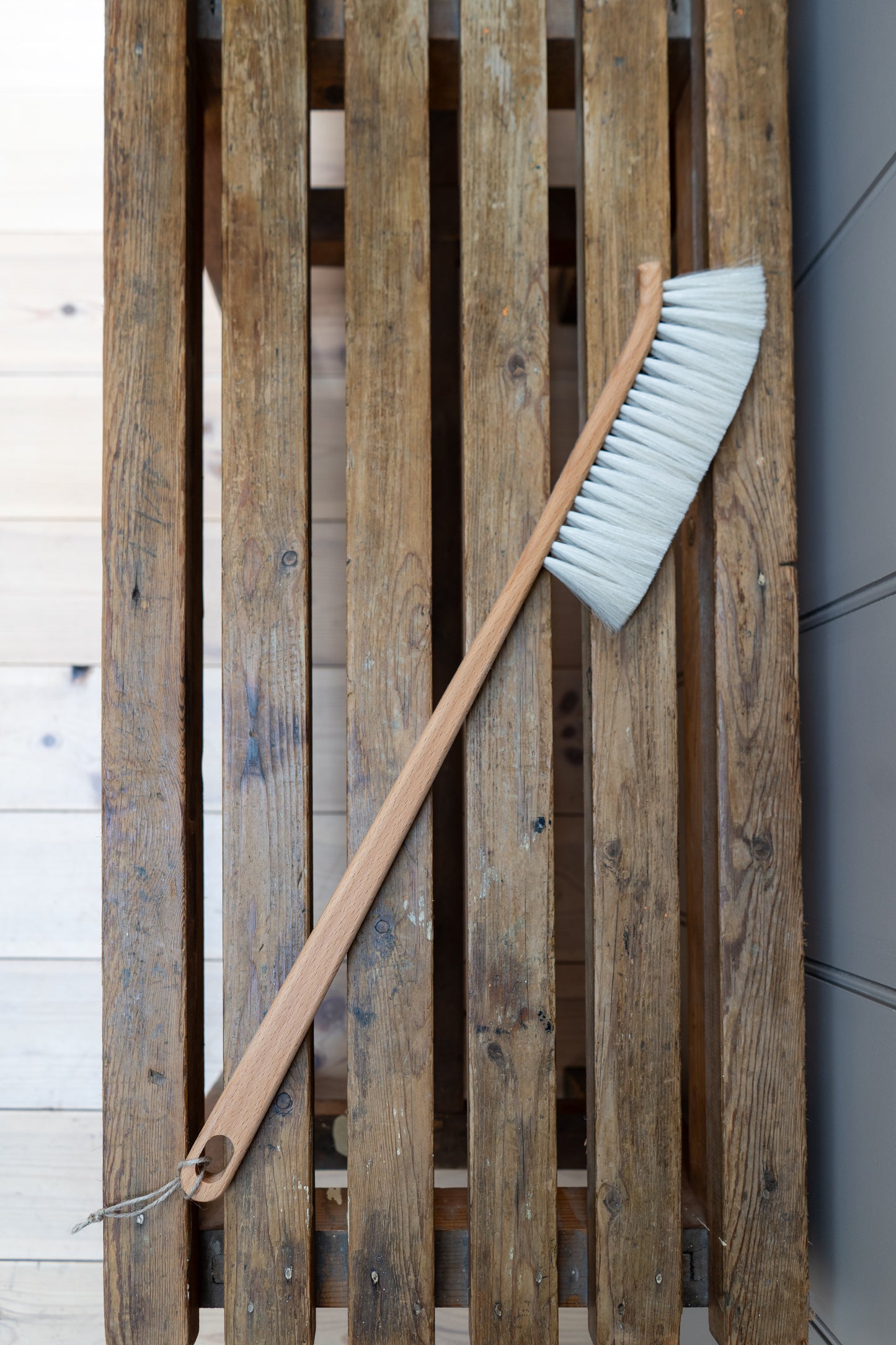 Dust brush with a white bristle head on a slatted bench.