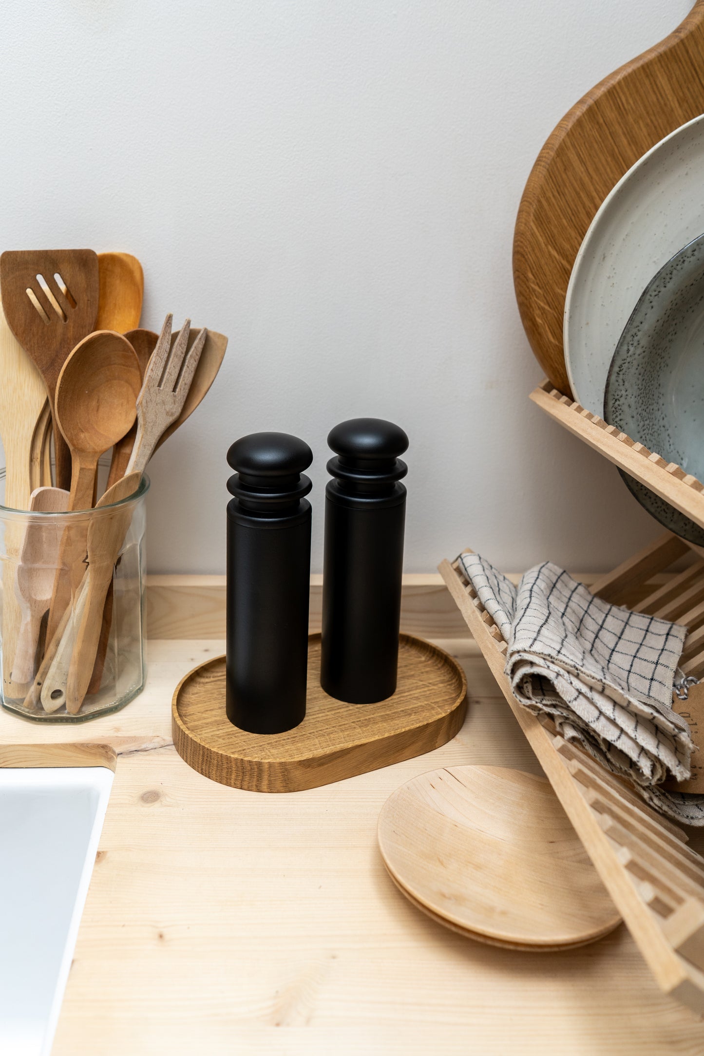 Wooden kitchen utensils in a jar on a wooden countertop with salt and pepper shakers.