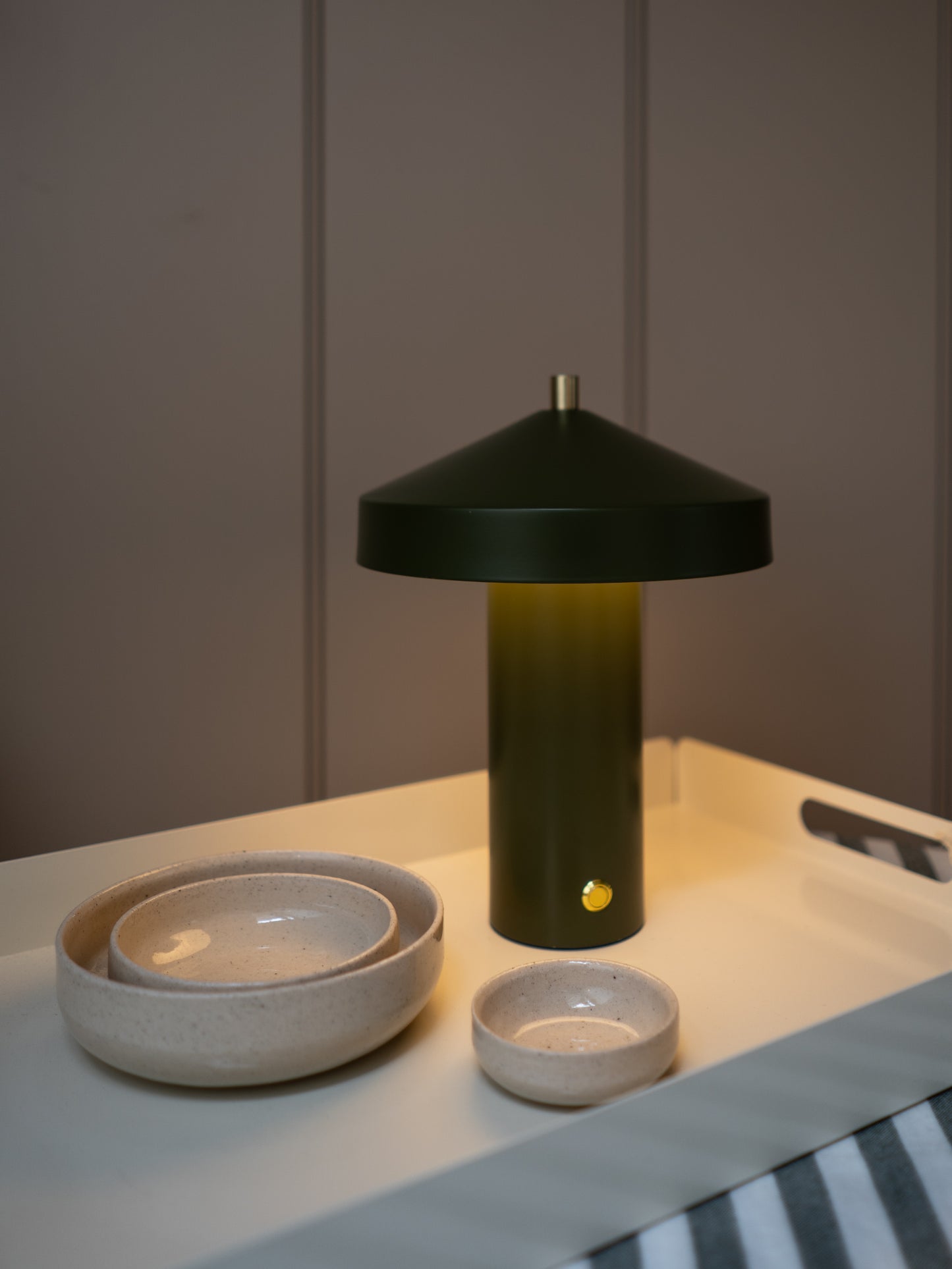Green lamp with a cone-shaped shade on a table next to ceramic bowls.