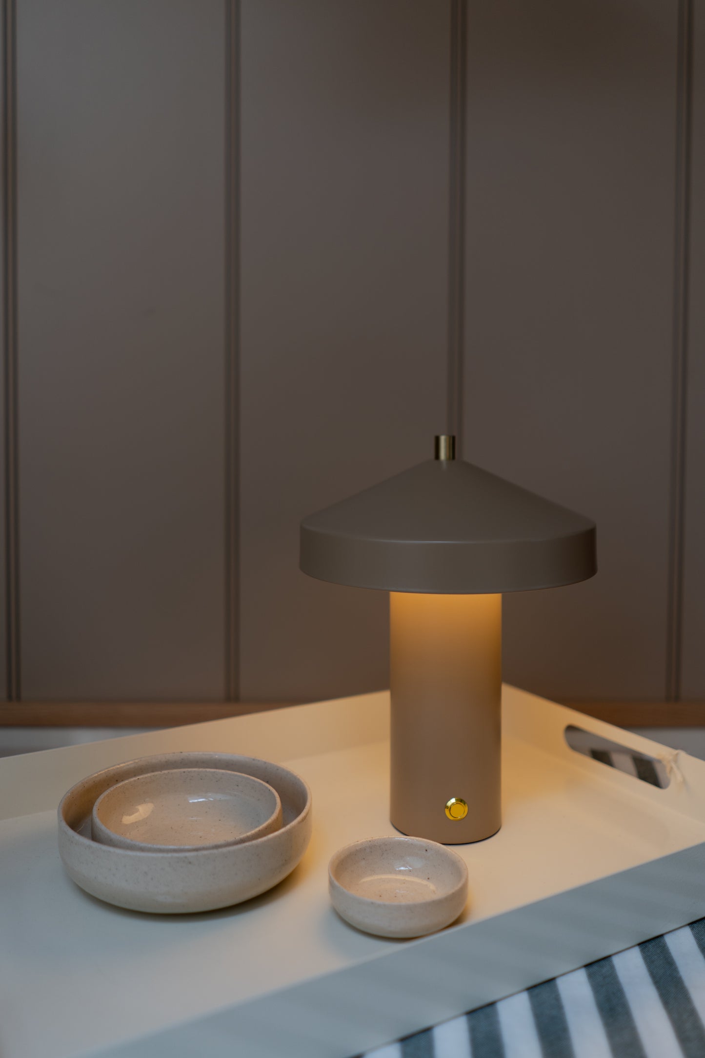 Table lamp on a surface with bowls and a striped fabric background