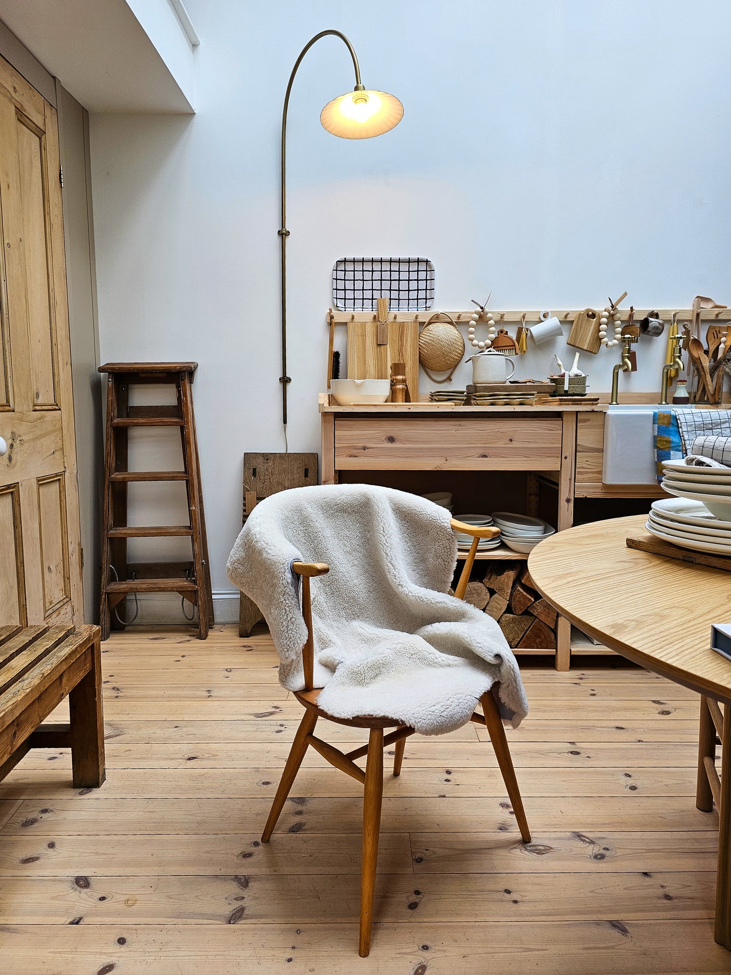 Wooden chair with a white sheepskin draped over it in a room with wooden floor and furniture.
