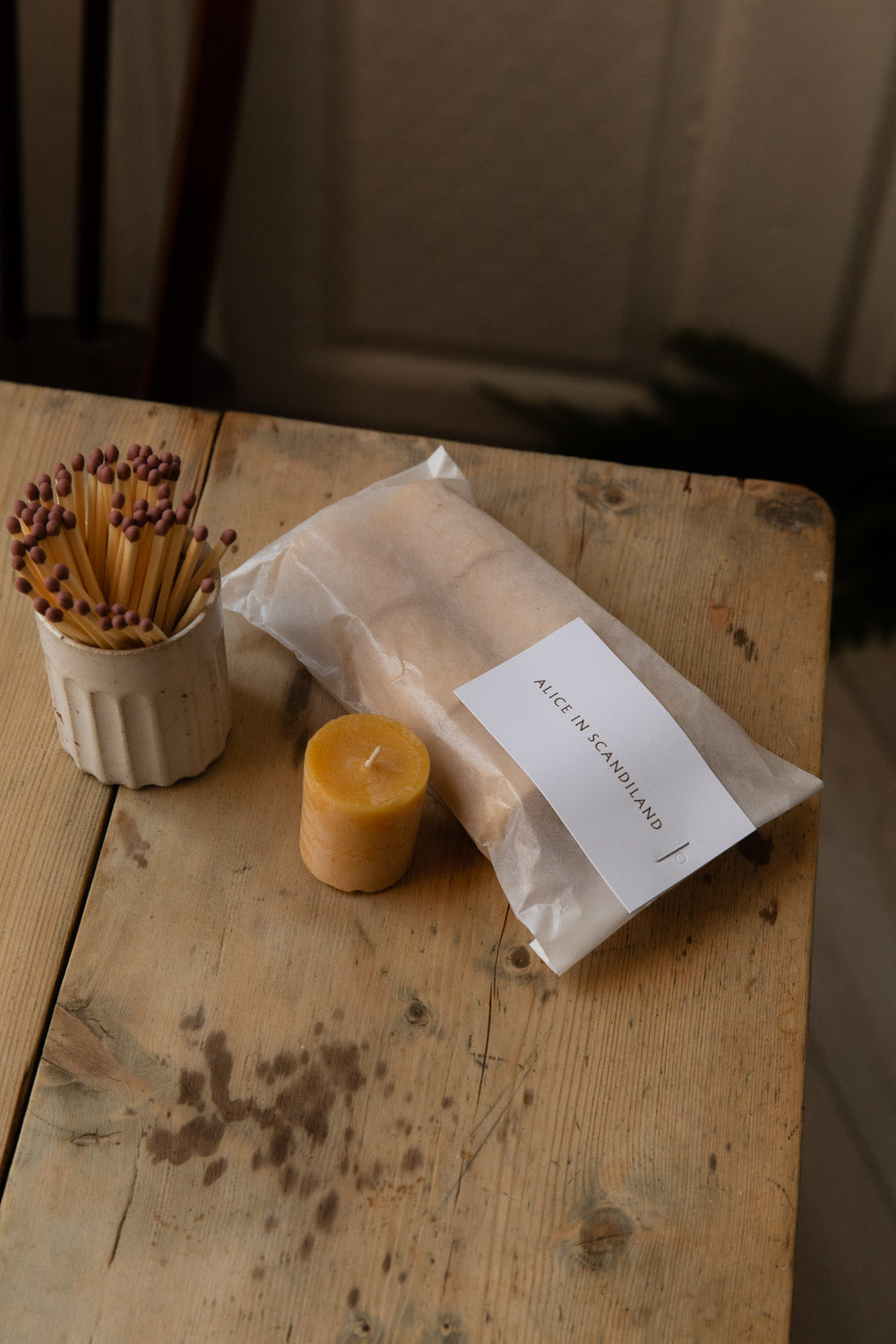 Pack of beeswax tealights beside a honey-coloured beeswax candle and a fluted match pot
