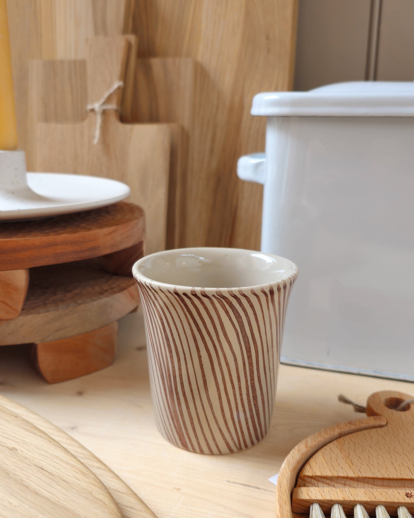 Diva mug with brown stripe pattern on a wooden kitchen shelf, styled in a kitchen setting with choppins boards, brushes, enamel bread bin and a candle.