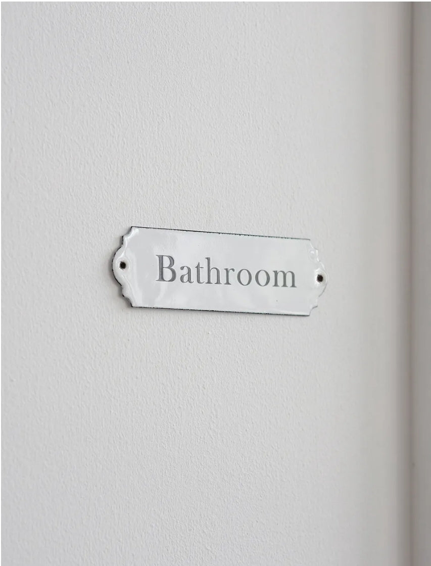 A rectangular enamel bathroom sign.