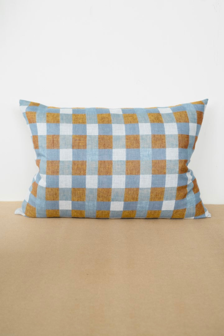 A rectangular linen cushion with a geometric pattern, displayed on a beige surface.