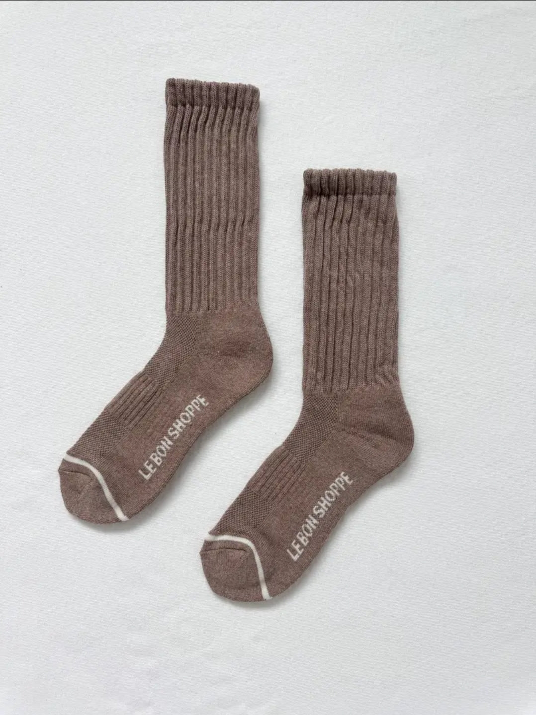 Pair of brown socks with white details on a light grey background.