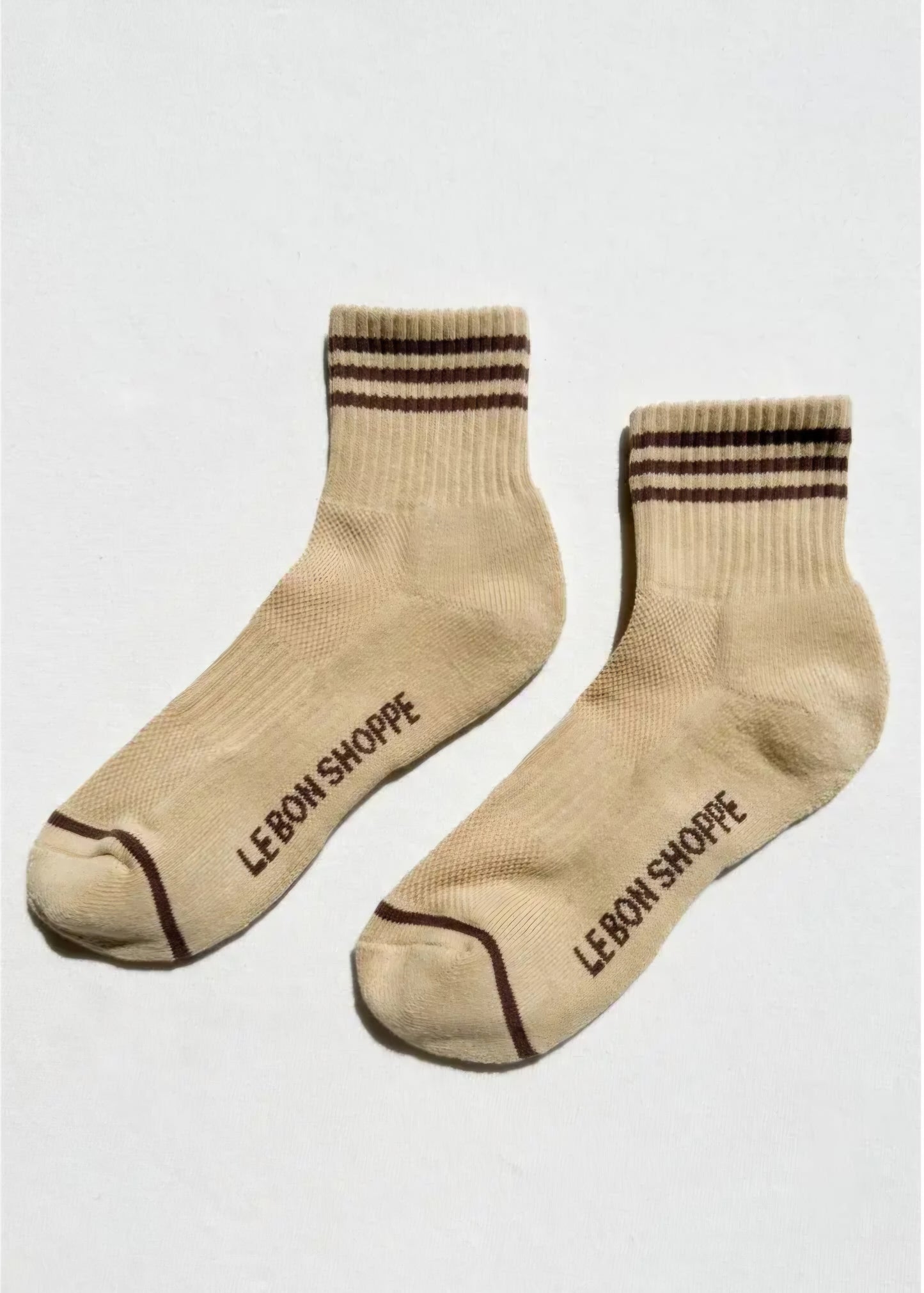 Light yellow socks with brown stripes and 'Le Bon Shoppe' branding on the sole on a white background.