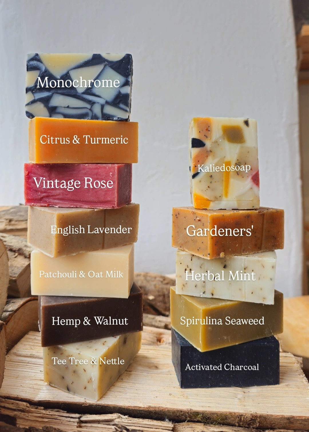 Stacks of variously scented soaps on a wooden surface with labels.