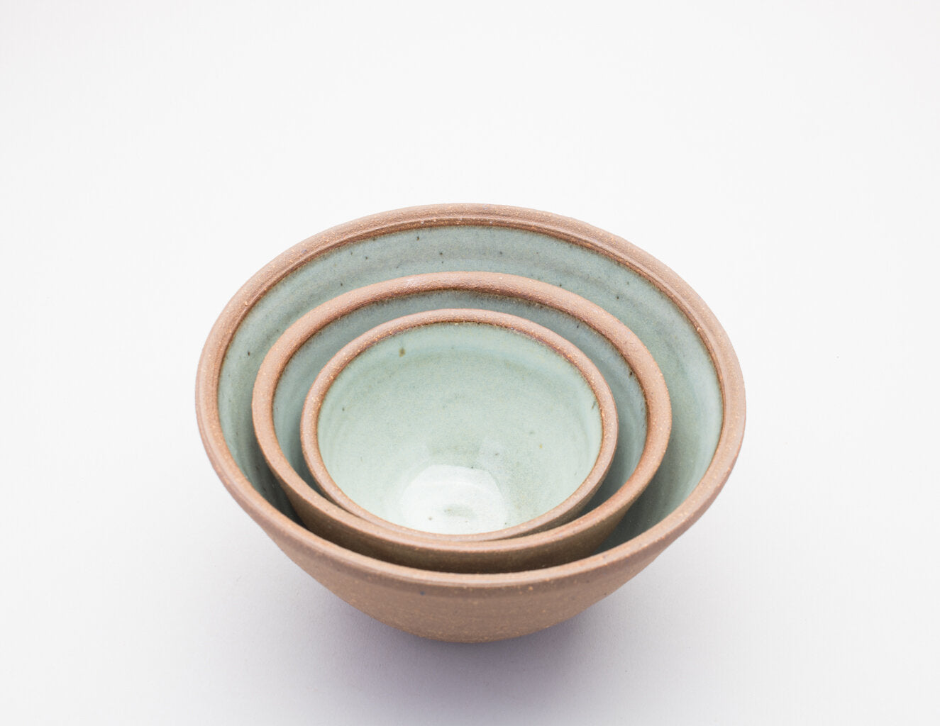 Three Leach Pottery prepping bowls nesting inside of one another on a white background.