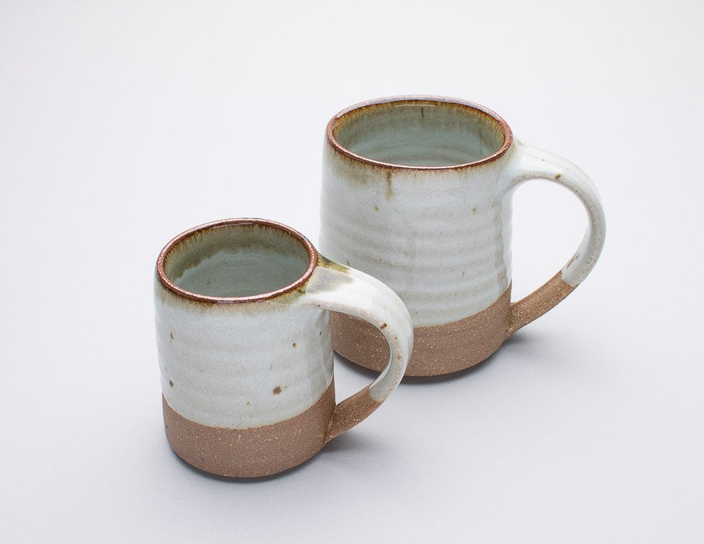 A Leach Pottery dolomite espresso mug and normal size mug displayed against a white background.