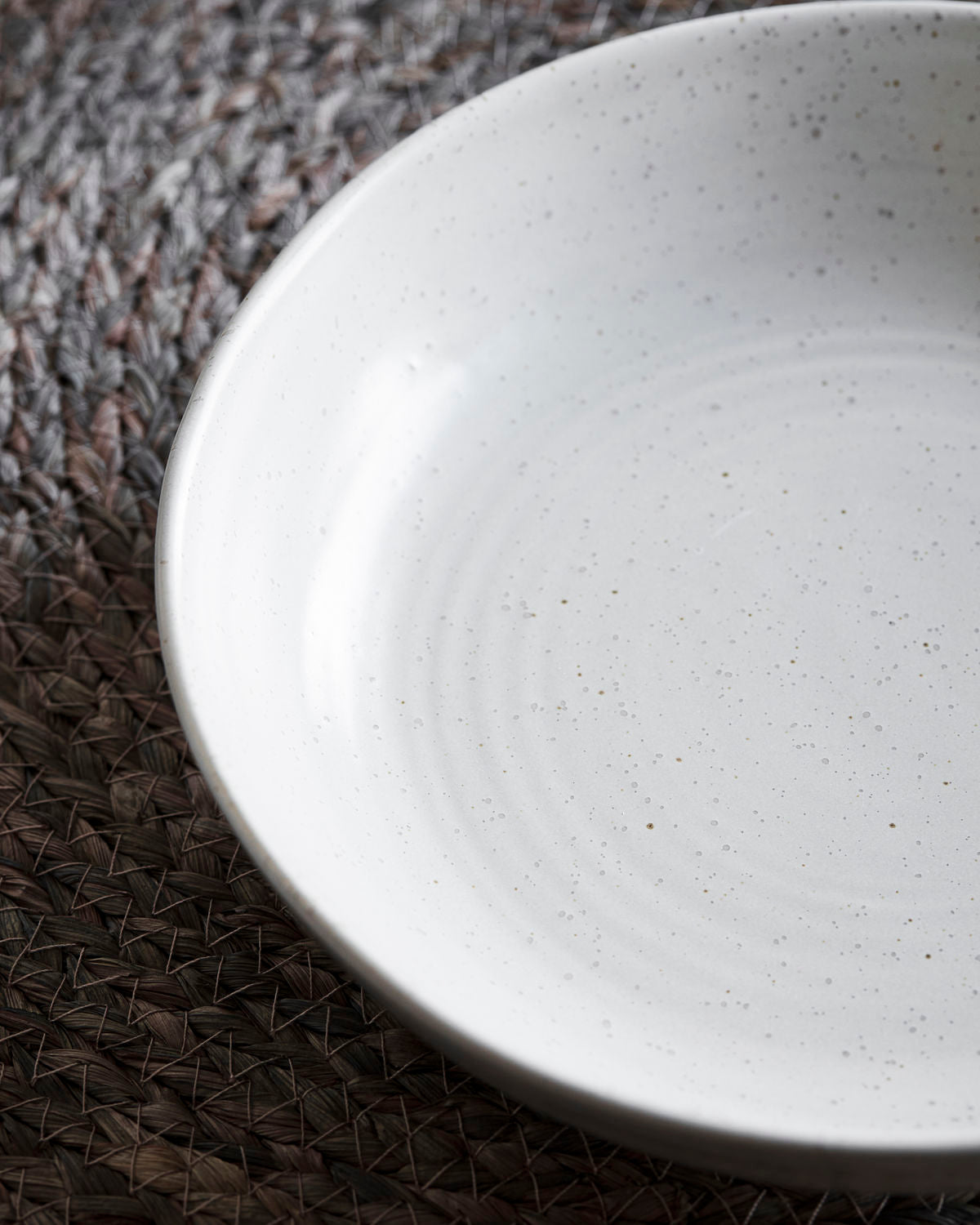 Close up of a white speckled stoneware bowl.