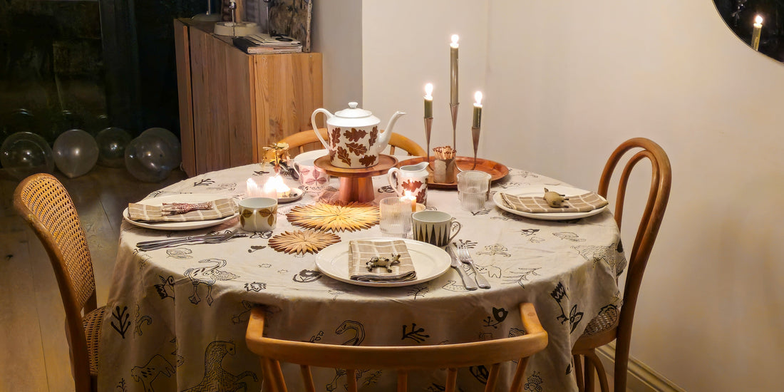 Candlelit birthday breakfast table laid the night before, with a leaf-print teapot and starburst trivets