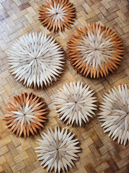Handmade two-tone wooden starburst trivet held in hand against a white background