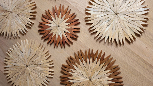 Handmade wooden starburst trivets in natural and two-tone Carpathian beechwood on an oak table