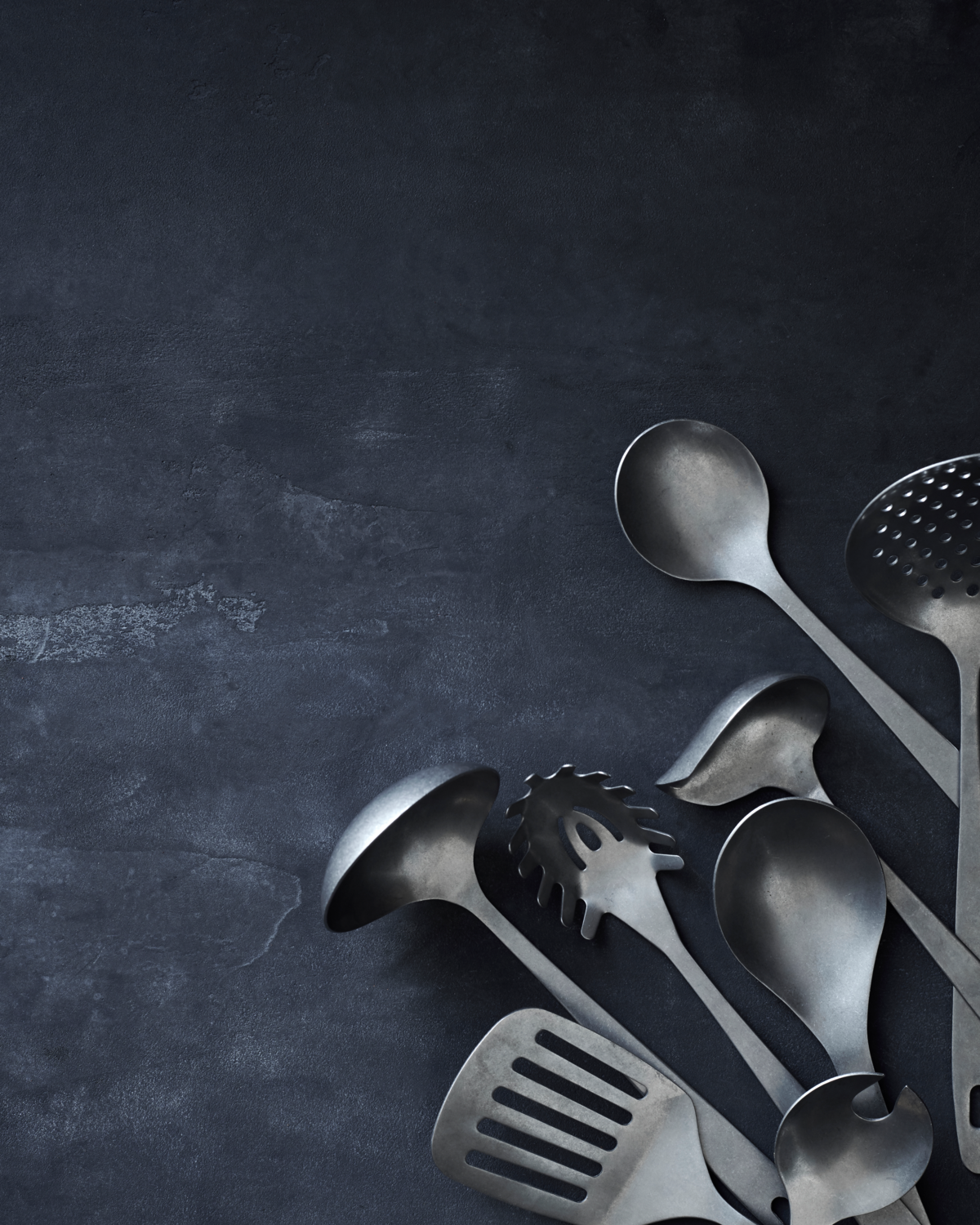 Set of metal kitchen utensils on a dark gray background