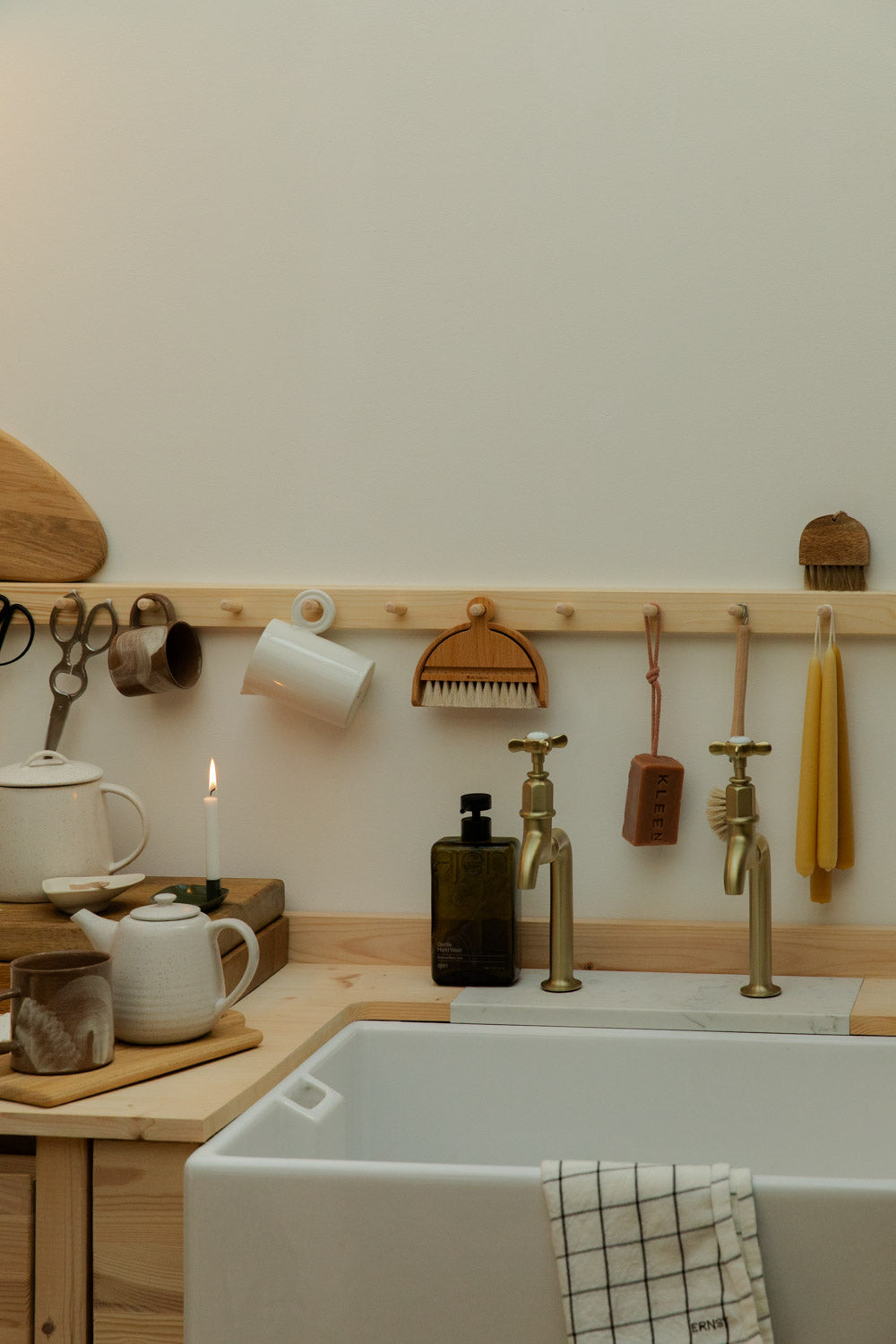 Kitchen corner with a sink, wooden shelves, and various kitchen items.