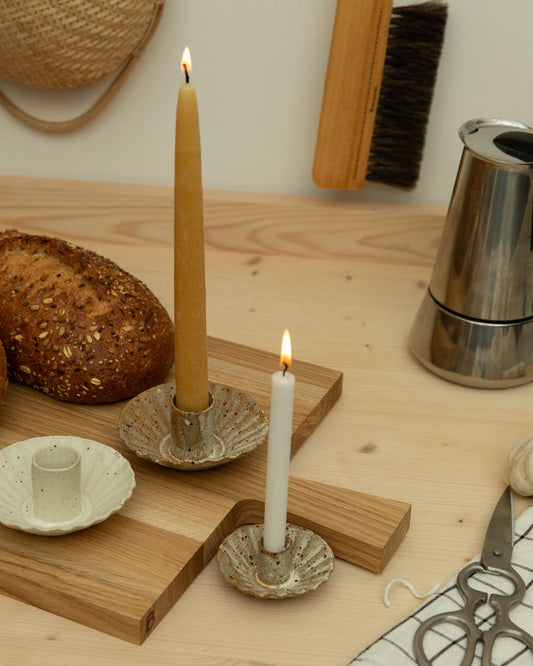 Wooden surface with bread, candles, and kitchen tools on a neutral background