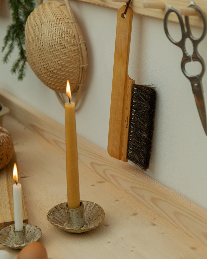 Candle on a wooden surface with a wall-mounted tool rack in the background