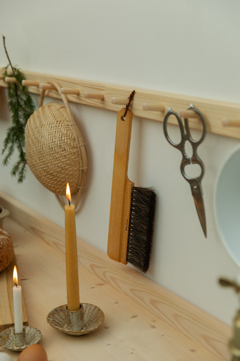 Candle on a wooden surface with a wall-mounted tool rack in the background