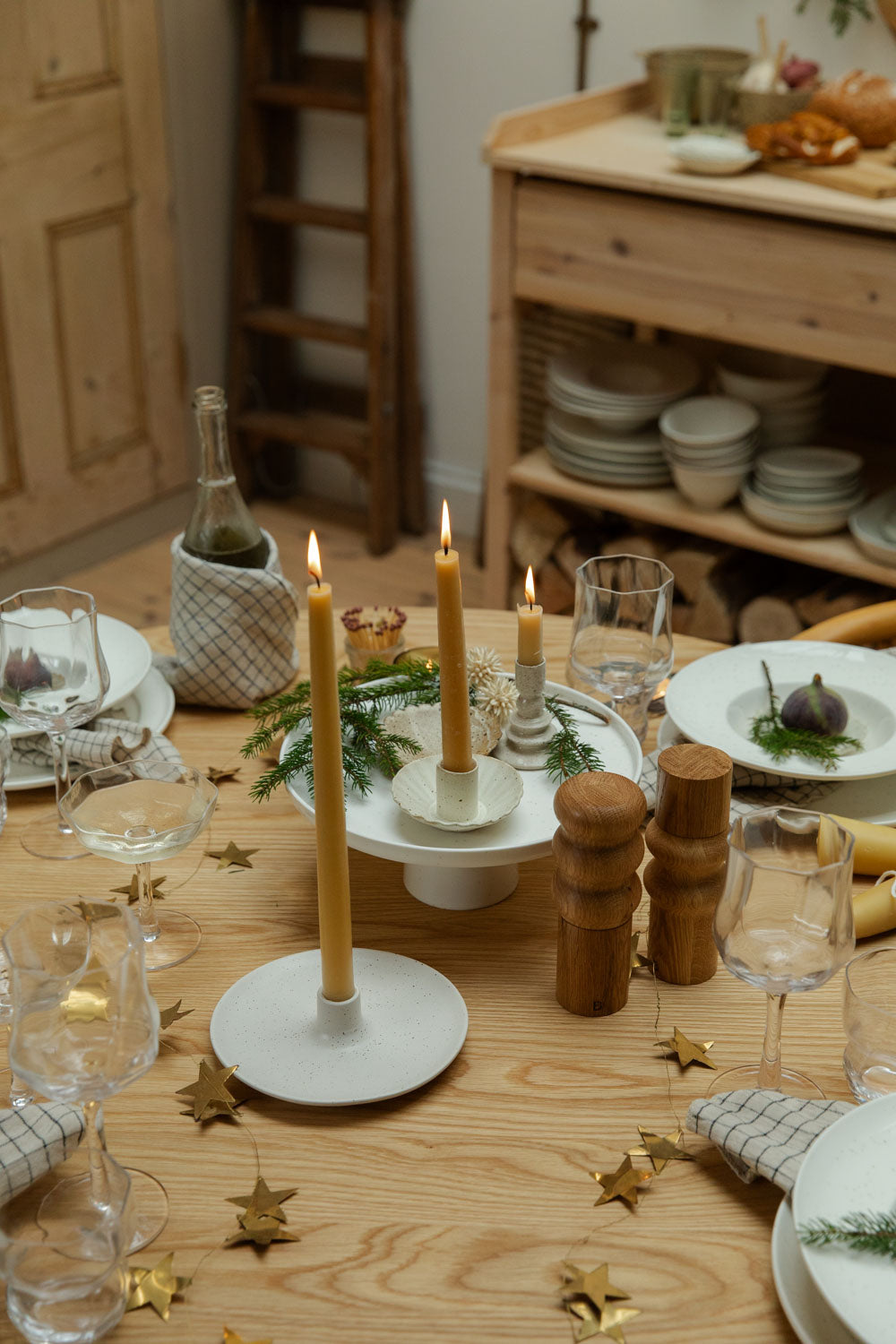 Dining table set for a meal with candles, plates, and glasses.